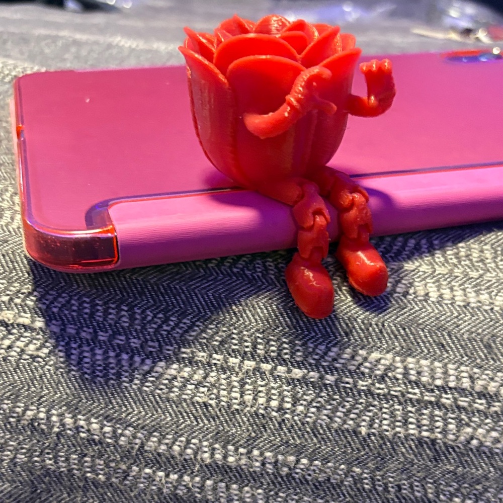 Red Rose-Shaped buddy sits with dangling legs holding up a heart sign 3D printed